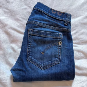 Blå jeans från Dondup  - Snygga blå jeans från Dondup med klassisk femficksdesign och raka ben. Jeansen har kontrastsömmar och en diskret logga på bakfickan. Perfekta för dig som gillar en tidlös och clean look. Materialet är mjukt och följsamt jeans. Midjemått: 40 cm benlängd: 94 cm !!priset kan diskuteras!!