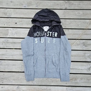 Hollister hoodie - Snygg zip-up hoodie från Hollister i svart och grå tvådelad design. Mjukt material, jättefint skick och knappt använd! Storlek S men passar även XS–M beroende på hur du vill att den sitter.