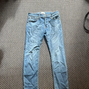 Slim Glenn jeans från Jack & Jones - Ljusblå slim fit jeans från Jack & Jones, modell Glenn. Klassisk femficksdesign med snygga kontrastsömmar och läderpatch bak. Jeansen har en smal passform och är tillverkade i mjukt denimtyg som sitter skönt hela dagen. Använd bara vid provning då de inte passade.