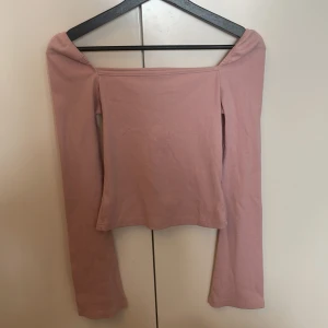 Rosa offshoulder topp från SHEIN - Supersöt ljusrosa offshoulder topp från SHEIN i ribbad bomullsmix. Långärmad och tight passform som sitter snyggt över axlarna. Perfekt att styla med jeans eller kjol för en trendig look.