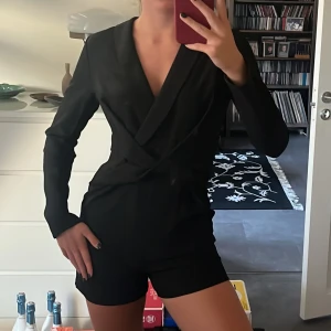 Svart omlott playsuit från NLY Trend - Snygg svart byxdress från Nelly med lång ärm och omlott framtill som ger en v-ringad look. Jag är 175