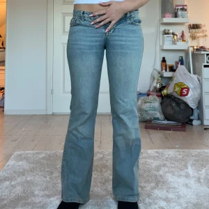 Blå bootcut jeans från Gina Tricot - Snygga ljusblå jeans från Gina Tricot med bootcut passform. Klassisk femficksmodell med coola ficklock och knappar bak. Jeansen har normal midja och är tillverkade i mjukt denimtyg. 