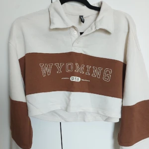 Croppad långarmad - Fin croppad långarmad pikétröja. Lite off white med brun ett brunt fält och text💗 bra skick!