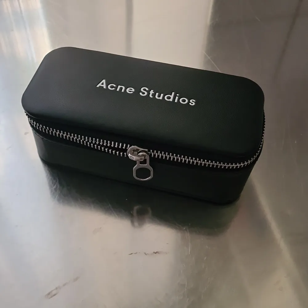 Acne Studios eyewear case(can also be used as a pencil case) in black with white embossed logo on top. Typical Acne Studios pink shade inside. 15cm long, 7cm wide and 5.50cm height. New condition. Selling due to not using sunglasses etc. . Övrigt.