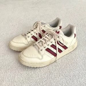Adidas-sneakers - Benvita sneakers med röda ränder, från Adidas! Samma som jag sålde förut fast en storlek större. Unik modell, köpta secondhand och är i använt men ändå bra skick! Tyvärr för små för mig 🤎