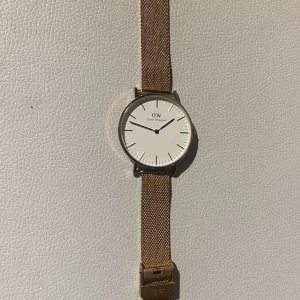 Daniel Wellington klocka - Klocka från Daniel Wellington i roséguld. Batteriet byttes för nåt år sedan så klockan går som den ska. Väldigt fint skick förutom någon repa på glaset. Justerbart band.