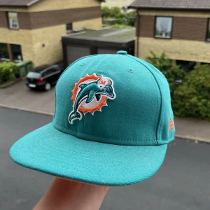 New Era Fitted - Säljer min nästan helt nya New era fitted keps. Endast använd 2 gånger. Storlek ”7 1/4” eller 57.7cm. Väldigt snygg. Laget är Miami Dolphins och den är köpt i Miami i USA. Den är äkta. Fler bilder eller frågor i DM. Kan gå ner i pris vid snabb affär🙏🏼🤞🏻