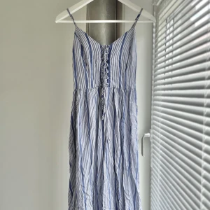 Strandklänning med snörning - Lång, somrig klänning köpt på New Look i London 💙🤍 Bara använd en gång och i perfekt skick. Justerbara axelband och snygg snörning där fram. Osäker på vilket material men tyget är ostretchigt och ganska tunt.