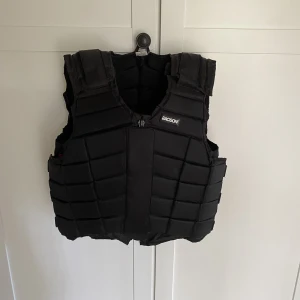 Ridväst  - Säljer nu min gamla Ridväst som jag hade när jag var liten och den är alldeles förstor för mig nu. Använd några år så i ganska bra skick, lite trasig vid kardborrebandet som man stänger västen me men dragkedjan funkar perfekt fortfarande. Köpte för 1200. 