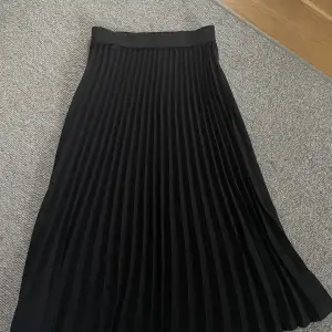 Lång svart plisserad kjol som längre inte används. 