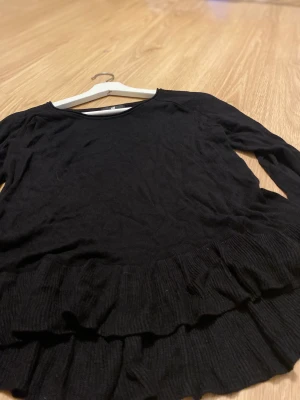Svart volang topp - En fin svart volang topp i finstickat material. Mycket fin topp i storlek S.