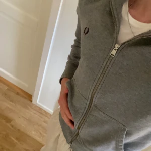Grå Fred Perry zip tröja  - En riktigt fet fred perry zip tröja som sitter sjukt bra och som är väldigt bekväm. Nypris kostar den runt 1599. Storlek XS, men passar S bra. Skick: 8/10 säljer för jag inte använder den längre. Om ni har frågor är det bara att skriva till mig, mvh Sam