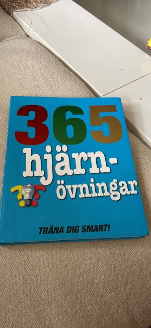 Bok hjärntränings - Utmana dig själv med 365 hjärnövningar. Gör en övning om dagen så märker du snart hur roligt det är att ha en vältränad, kvicktänkt hjärna.  Boken är full av kluriga och underhållande träningspass. Den dagliga uppgiften innehåller en gåta eller ett proble