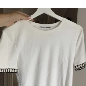 Zara t-shirt - Säljer denna fina t-shirt från Zara med svarta och guldiga detaljer🤍 Tröjan är  endast använd ett fåtal gånger och därför i nyskick.