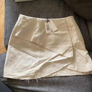 Kjol kort modell - Vit kjol från märket by Zoe. Oanvänd med lappen kvar. Gräddvit. 