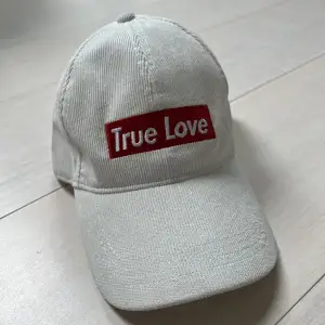 Knappt använd men har liten sminkfläck vid insidan av kepsen (syns ej på). Ribbad keps med texten ”True Love”. Klippt av lappen på insidan av kepsen så ser ej vilken storlek. Säljs då den ej används.