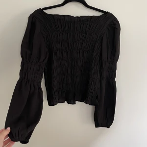 Svart blus - En svart blus med resår-detaljer, sitter jättefint! Använd ett fåtal tillfällen men inget som syns.
