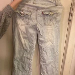 Lågmidjade bootcut ljusblåa Levi jeans - Lågmidjade bootcut jeans från Levi's med skit snygga fickor. Aldrig användt, i jätte bra skick men är tyvärr för korta för mig♡ Psa. Små i storleken! (Pris kan diskuteras)   Måt: Total längd: 91cm  Midja: 34cm (platt) Lår: 18cm (platt) 