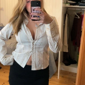 Figursydd Skjorta - SÅ snygg figursydd randig skjorta. Stretchigt material med guld och bruna ränder. 