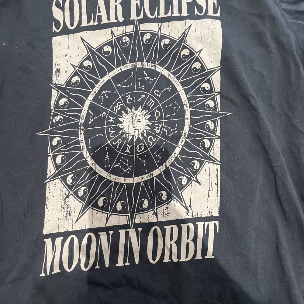 En svart t-shirt med ett astrologiskt tryck på. T-shirts.