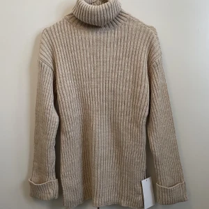 Stickad tröja - Jättefin stickad tröja med polokrage, slits och vida armar från NA-KD, helt oanvänd. Prislapp kvar. 