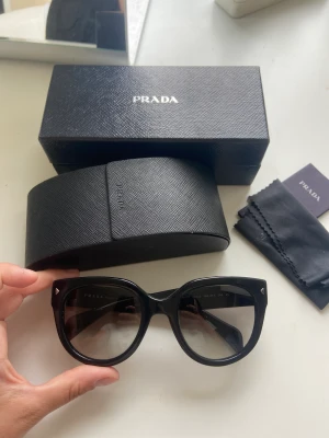 Prada solglasögon  - Säljer ett par super fina prada solglasögon som tyvärr säljs då min mamma fick dom på morsdag men vill ha ett par bruna. Allt på bilden medföljer 