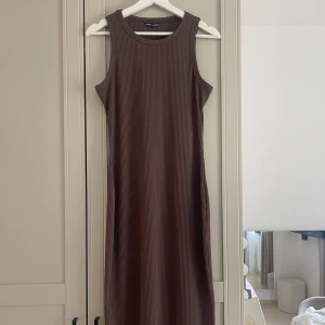 Brun klänning  - Säljer denna bruna klänning, sitter tajt och går ända ner till vaderna. Klänningen är ribbad i materialet.🤍aldrig använd! Passar en som bär storlek M
