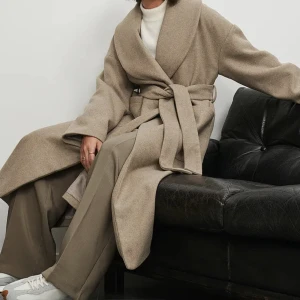 Beige lång kappa  - Kappa från NAKD, Sofia Coelhos kollektion. Använd några få gånger, så i nyskick. Säljes då jag vill ha annan kappa i vinter. Nypris 1199