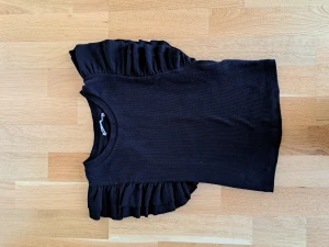Svart topp med volangärmar  - Svart topp i slim fit med volangärmar. Storlek S. Använd ett fåtal gånger. 