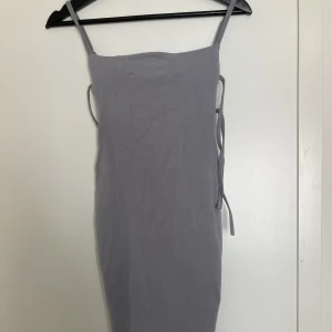 Oh polly klänning - ny - Klänningen har lappen kvar! Tättsittande, justerbara stroppar, och låg rygg med knytdetaljer. Går över knäna. Verkligen megafin, med fin gråviolet färg! 