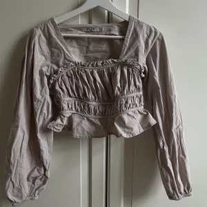 Söt långärmad topp från NAKD - Beige långärmad topp från NAKD med volanger. Använd ett fåtal gånger, passar till vardag samt uppklädd, I toppenskick, storlek 34🥰