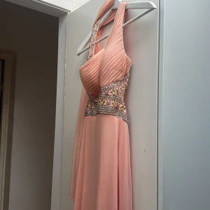 Vacker klänning till fest eller bröllop - En otroligt vacker klänning med fina detaljer. Vadderad i bysten och lite djupare skärning i ryggen. Tunn "skarf" att ha över axlarna till ingår. Slits framtill. Detta är klänningen för det lilla extra