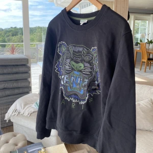 Kenzo tröja  - Säljer Kenzo tröja i grön/blått/svart. Tröjan är i väldigt bra skick då den knappt blivit använd! Pris kan diskuteras. 