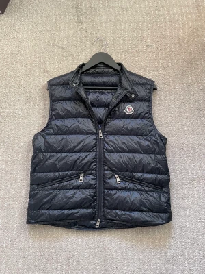 Moncler Gui väst  - Säljer denna Moncler Gui väst som är i väldigt bra skick! Storlek 2! Tillkommer påse där man lägger västen i samt kvitto från NK!  Hör gärna av dig om du har frågor!