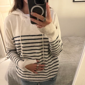 Stickad tröja  - En jätte fin randig stickad tröja med luva! Jätte fina detaljer på armarna längst ner vid händerna med guldknappar! 