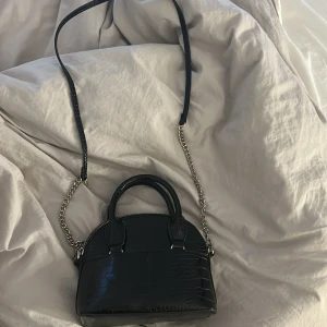 Väska  - En svart snygg väska från zara. Säljer den då den aldrig nästan kommit till användning. Kan ha axelband men man kan också ha den utan.🙌🙌FRAKT SKA BETALAS ❤️❤️