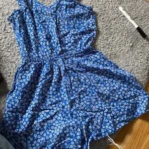 Byxdress - En blommig blå byxdress ganska liten i midjan 