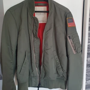 Ralph lauren jacka - En grön ralph lauren jacka, har ett litet brännmärke längst ner på jackan. 