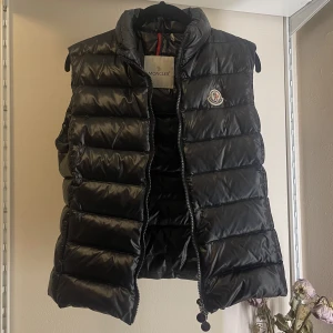 Moncler väst - Svart moncler väst i storlek 2 (motsvarande M). Knappt använd men läppen har åkt av på insidan. Kan skicka äkthetsbevis privat! Pris kan diskuteras!