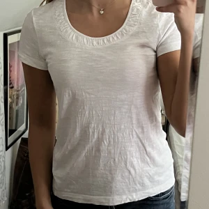 Vit T-shirt - Supersöt vit T-shirt med detalj runt urringningen. Begagnat skick, men inga fläckar eller hål! Storlek 40 men sitter mer som en 36🫶💕