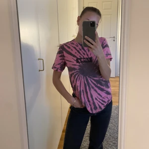 T-shirt - En rosa/brun batikfärgad t-shirt med tryck.