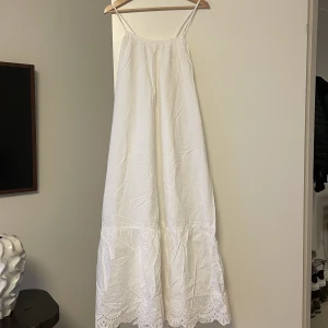 Lång Sommarklänning - Vit sommarklänning som man kan justera med knytning av band i ryggen. 
