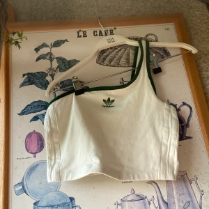 Adidas oneshoulder shirt - Extremt gulligt oneshoulder linne från adidas. I grönt å vitt med fina vita ränder. Sitter extremt fint 🔥pris kan diskuteras!