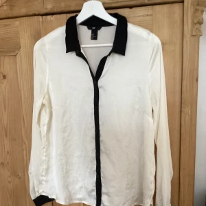 Snygg vit skjorta  - Vit skjorta med svarta slag i silkigt material. Liten 38:a
