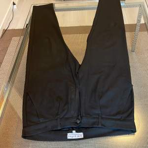 Svarta tapered kostymbyxor med pressömmar upptill. 