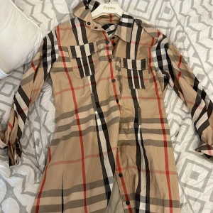 Burberry klänning - En burberry klänning jag haft i min garderob i några år. Sällan använd o i bra skick, ej sliten. Snyggt med ett bälte runt midjan.