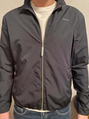 Vindjacka Gant Mörkblå  - Vindjacka från Gant | Storlek: 15/16 (passar S) - Skicket på jackan är väldigt bra inga defekter -Vårat pris 300kr - Nypris 799kr - Modellen är 180cm.