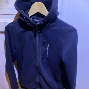 Sail racing kofta marinblå - Tja säljer nu denna sail racing koftan då den blivit för liten! Skicket är bra men använt skulle säga 7/10. 160 är storleken vilket motsvarar ungefär Xs. Hör av dig för minsta fundering 