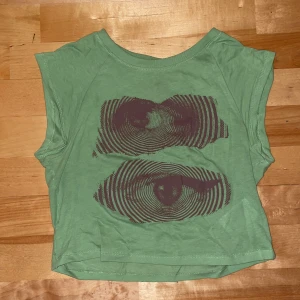 Grön T-shirt  - Det är en kort grön t-shirt med bruna ögon på. Jag skulle beskriva den som grunge 