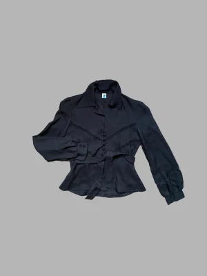 Detaljfin svart blus - Säljer denna jättefina svarta blus då den är för liten för mig i ryggen. Har jättefina detaljer i spets, lite transparent tyg och knytning. Står storlek 38, men skulle nog säga 36.